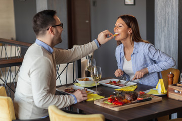 Obraz na płótnie Canvas Couple tasting each other's food in restaurant