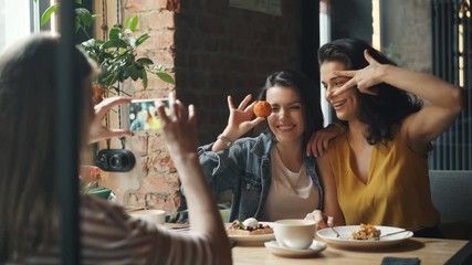 Attractive young ladies taking photos in cafe posing for smartphone camera smiling laughing having fun enjoying life and friendship. Youth and photograph concept.