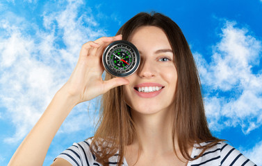 Beautiful young woman is holding a compass near her face. Concept