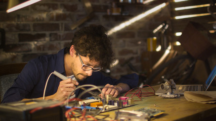 Student is studying electronics and soldering a circuit board in a garage.