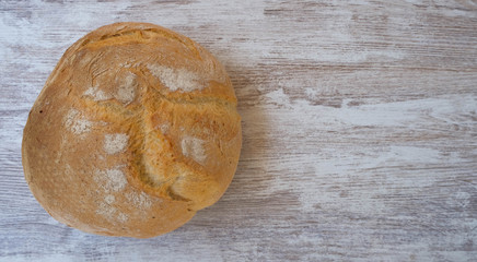 Top view on rustic bread on a natural wooden background. Home baked bread isolated on natural textured background. Round homemade bread. Fresh bakery image with copy space for your text.