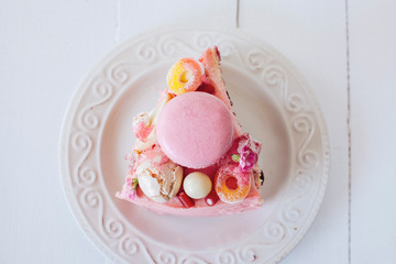 Piece of pink cake. Decoration from sweets, macarons, marshmallows, white chocolate. Sweet birthday...