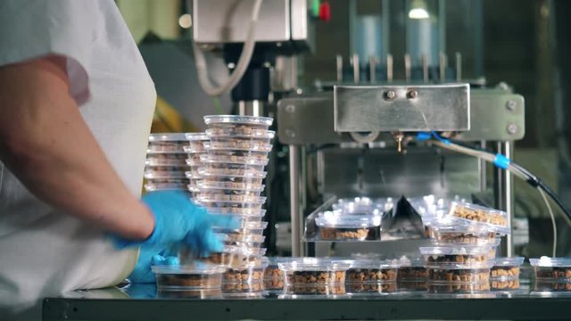 Worker is stacking plastic boxes with bread snacks
