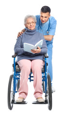 Young caregiver with senior woman on white background