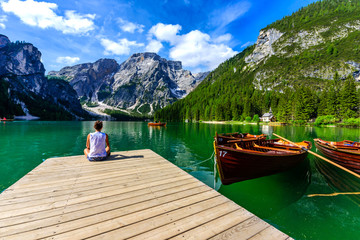 Woman relaxing on Pier at Lake Braies also known as Pragser Wildsee  in beautiful mountain scenery. Amazing Travel destination Lago di Braies in Dolomites, South Tyrol, Italy, Europe.