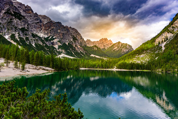Fototapeta na wymiar Lake Braies also known as Pragser Wildsee in beautiful mountain landscape. Sun and cloud scenery at sunset time. Amazing Travel destination Lago di Braies in Dolomites, South Tyrol, Italy, Europe.