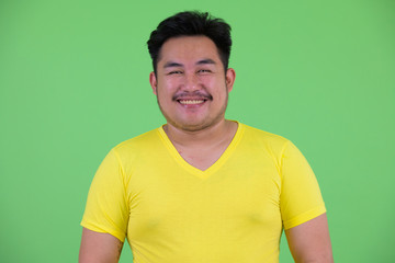 Face of happy young handsome overweight Asian man smiling