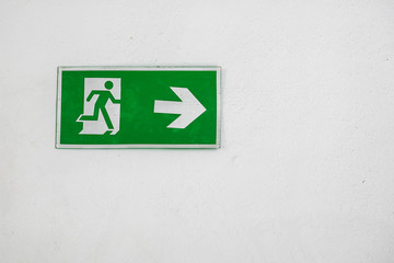 Old Warning Plastic Fire Exit Sign on the White Wall