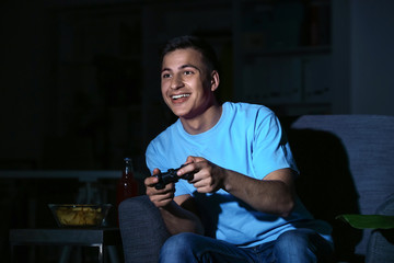 Young man playing video game late in evening