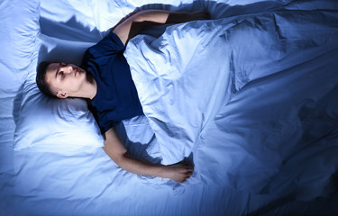 Young man sleeping in bed at night