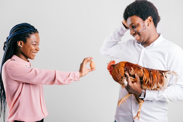 Happy african american couple with eggs and rooster isolated on white in studio