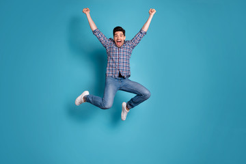 Fototapeta na wymiar Full length body size view photo charming nice youngster raise fists shout yeah celebrate wonderful news thrilled candid checked shirt jeans sneakers free time holiday isolated blue background
