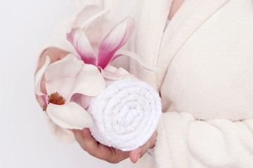 towel and magnolia flower in female hands, concept of massage, spa, on a light background, copy space