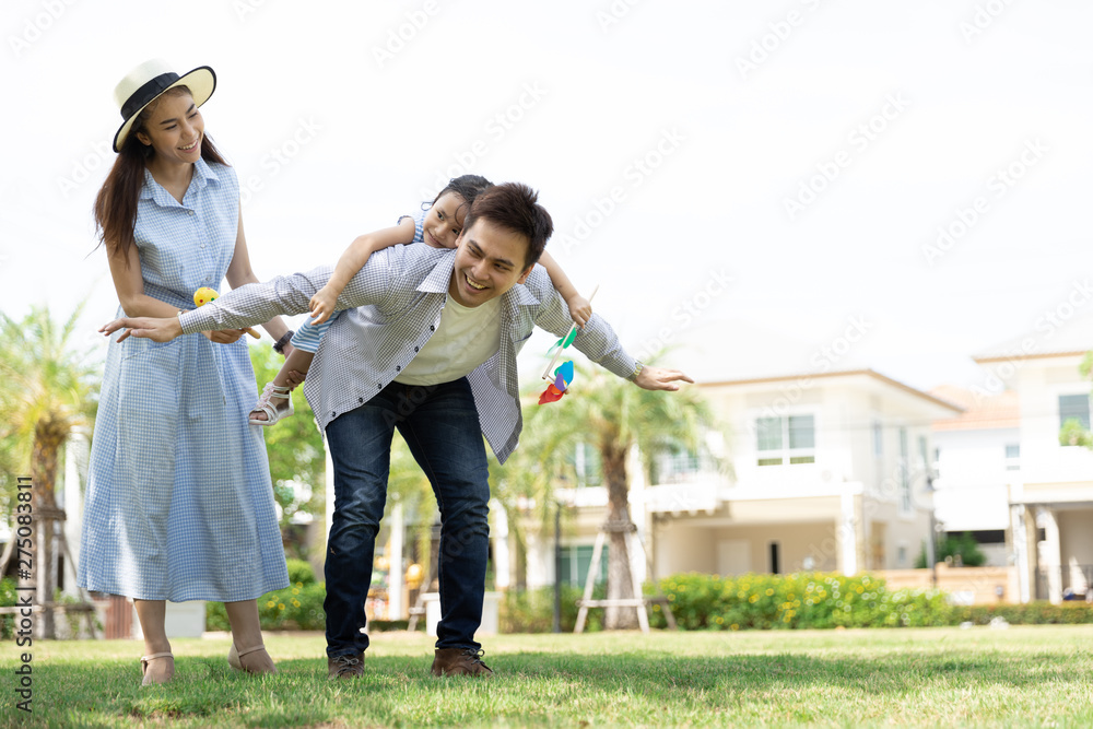 Wall mural happy asian family. father gave his daughter a piggyback at a park at natural sunlight background an