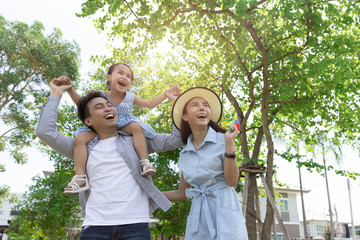 Happy Asian family. Father gave his daughter a piggyback at a park at natural sunlight background...