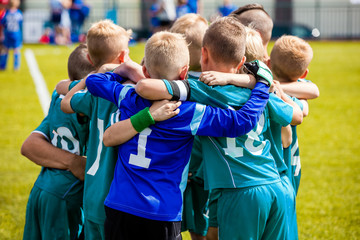 Boys' sports team huddling. Children playing sports in a team. Team sports for kids. Children sports football soccer team