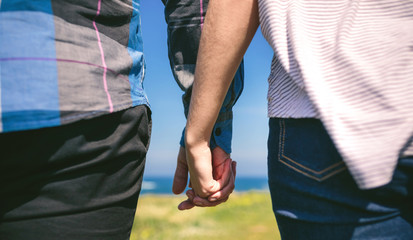 Detail of young unrecognizable couple holding hands outdoors