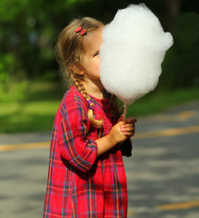 Happy toddler girl eating cotton candy