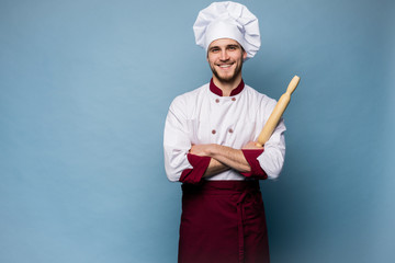 Naklejka premium Portrait of positive toothy chef cook in beret, white outfit having tools in crossed arms looking at camera.
