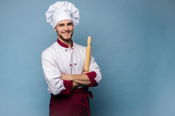 Portrait of positive toothy chef cook in beret, white outfit having tools in crossed arms looking...