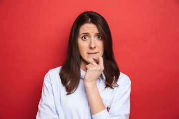 Amazing confused young beautiful woman posing isolated over red wall background.