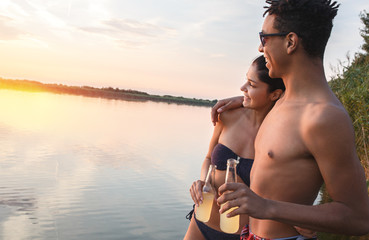 Young mixed race couple  having fun on the pier by the lake .Enjoying the sunset.