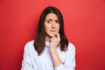 Amazing confused young beautiful woman posing isolated over red wall background.