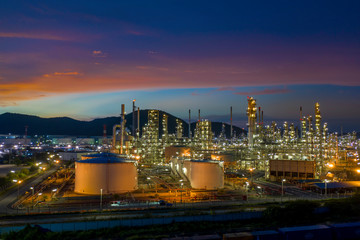 Fototapeta premium Aerial view. Oil refinery factory and oil storage tank at twilight and night. Petrochemical Industrial.