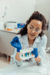 Nice young woman holding a test tube rack