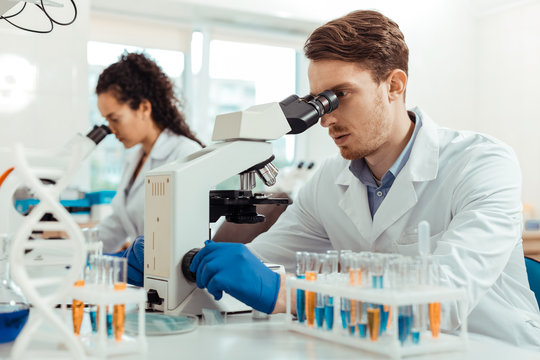 Handsome young man looking into the microscope