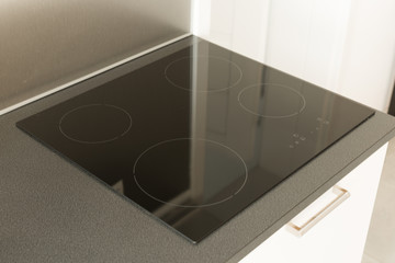 Stove with induction cooktop. Modern black induction cooker on black countertop.