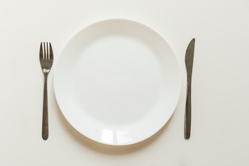 Empty plate, fork, knife, cutlery on white background top view. Table serving concept.
