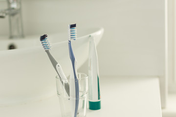 Toothbrushes in a glass in the bathroom interior. A pair of toothbrushes. Dental concept. Copy space.