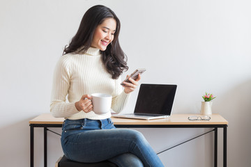 Young happy Asian woman using smart phone.