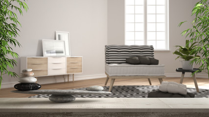 Wooden vintage table or shelf with stone balance, over blurred modern living room with wooden details and parquet floor, feng shui, zen concept architecture interior design