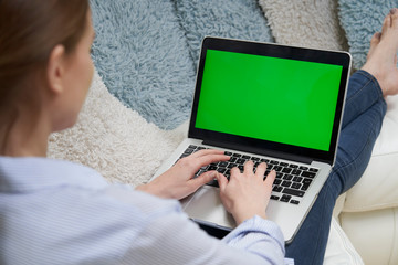 Over The Shoulder View Of Woman Lying On Sofa Using Green Screen Laptop