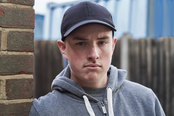 Portrait Of Teenage Boy Leaning Against Wall In Urban Setting