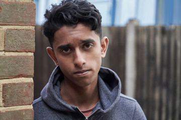 Portrait Of Teenage Boy Leaning Against Wall In Urban Setting