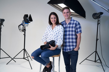 Portrait Of Female And Male Photographers In Studio For Photo Shoot With Camera And Lighting...