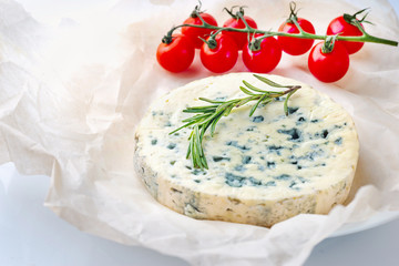 Fototapeta na wymiar Blue cheese with cherry tomatoes, rosemary on paper