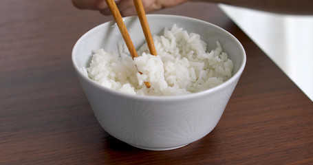 Closeup of woman eating rice from bowl with fork