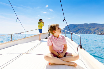 Two little kid boys, best friends enjoying sailing boat trip. Family vacations on ocean or sea on...