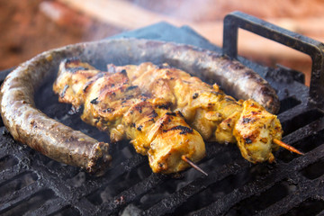 Barbecue - a sausage and chicken skewers on a metallic grid