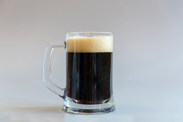 Glass of dark beer on a gray background