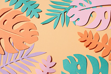 Paper tropical plants leaves on the orange background. Summer concept Top view © mariarom