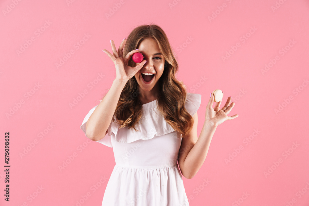 Wall mural image of happy joyful woman wearing white dress smiling at camera and holding macaroon biscuits