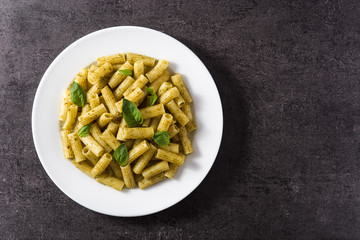 Penne pasta with pesto sauce on black background. Top view. Copyspace