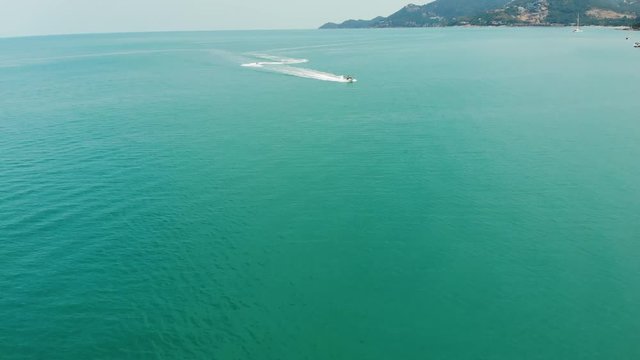 Anonymous person riding water scooter. Unrecognizable tourist riding modern water scooter on blue water of sea on resort. Koh Samui paradise exotic Chaweng beach drone view