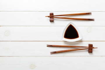 Soy sauce with chopsticks on white wooden table background
