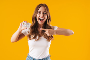 Photo of lovely young woman rejoicing while holding and pointing finger at credit card